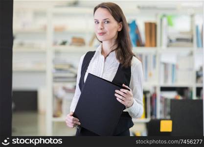 Business woman standing in office holding folder of files. Business woman holding files