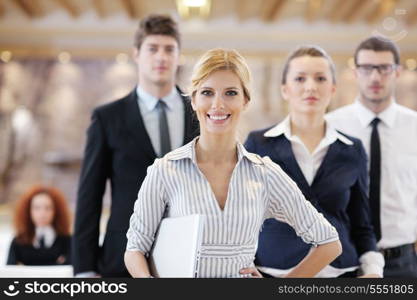 business woman standing with her staff in background at modern bright office conference room