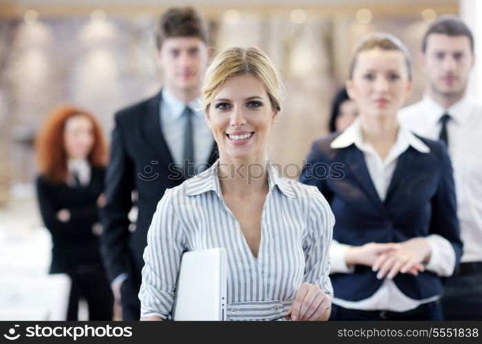 business woman standing with her staff in background at modern bright office conference room