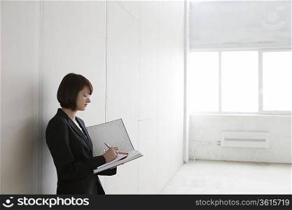 Business woman stands with file in empty warehouse