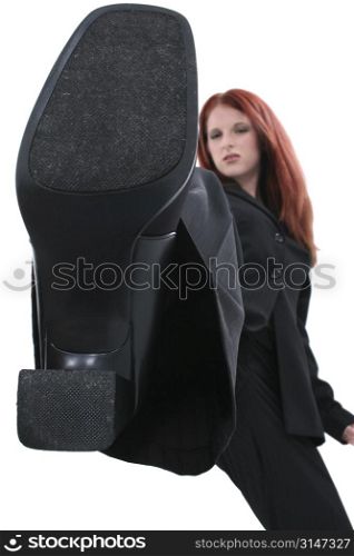 Business woman stopping on the camera. Metaphor or conceptual image for &acute;squashing the competition&acute; or &acute;stepping on the little guy&acute;.