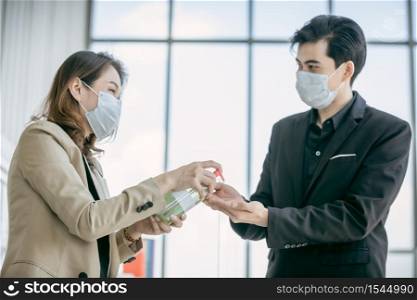 Business woman to share alcohol gel to business man at the office to protect covid-19 coronavirus.Social and business distancing new normal lifestyle.