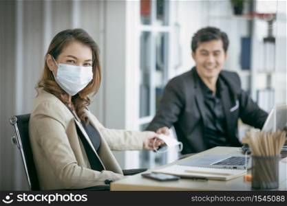 Business woman to share face mask with workmate for protect coronavirus covid-19 pandemic. Social and business distancing new normal lifestyle.