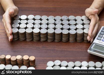 Business woman using calculator counting lots stack coins on wooden desk background texture, Money for business planning investment and saving concept