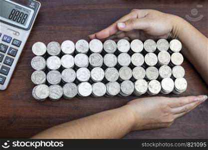 Business woman using calculator counting lots stack coins on wooden desk background texture, Money for business planning investment and saving concept