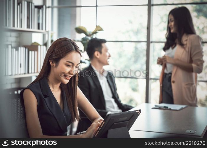 Business woman using modern digital tablet while coworker interacting in the background in the office , Teamwork meeting and partnership concept.