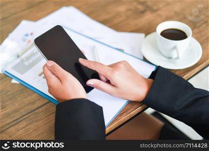 Business woman using smartphone and working in office with business report on the table desk with coffee cup / women uses technology mobile phone