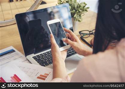 Business woman using smartphone, laptop on office desk. Female freelance reading financial graph charts Planning analyzing marketing data. Hands of young woman working in office firm business info.