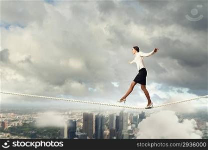 Business woman walking tightrope