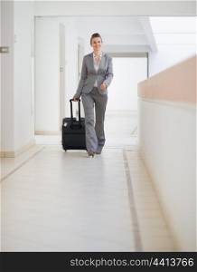 Business woman walking with bag on wheels