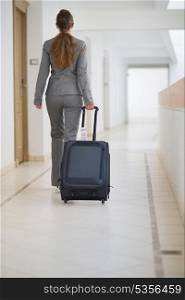 Business woman walking with bag on wheels. rear view