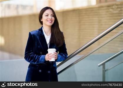 Business woman wearing blue suit taking a coffee break outside her office. Lifestyle concept.. Business woman wearing blue suit taking a coffee break outside her office.