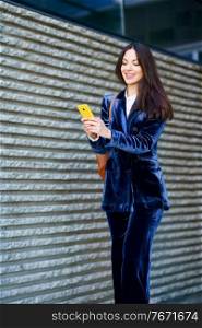 Business woman wearing blue suit using smartphone in an office building. Lifestyle concept.. Business woman wearing blue suit using smartphone in an office building.