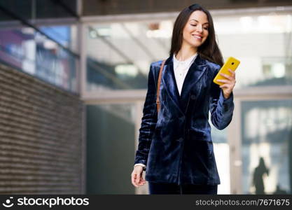 Business woman wearing blue suit using smartphone in an office building. Lifestyle concept.. Business woman wearing blue suit using smartphone in an office building.