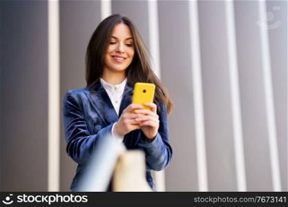 Business woman wearing blue suit using smartphone in an office building. Lifestyle concept.. Business woman wearing blue suit using smartphone in an office building.
