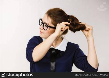 Business woman wearing eyeglasses, accountant or teacher fixing her hair style. Gray background. Business woman fixing her hair