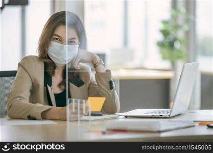 Business woman wearing face mask and using partition on table for protect coronavirus covid-19 pandemic. Social and business distancing new normal lifestyle.