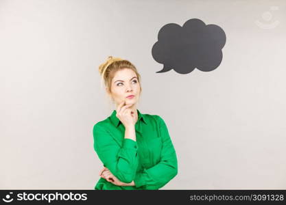 Business woman wearing green jacket and eyeglasses intensive thinking finding great problem solution, black thinking or speech bubble next to her.. Business woman intensive thinking