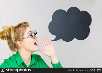 Business woman wearing green shirt and eyeglasses yelling telling something someone, black thinking or speech bubble next to her.. Business woman yelling telling something