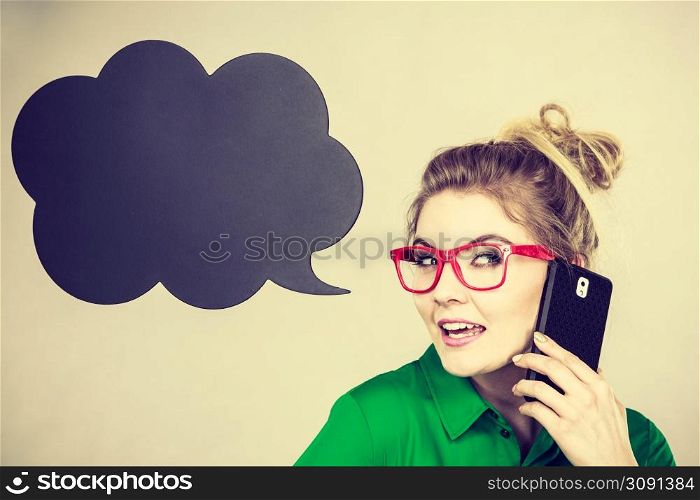 Business woman wearing green shirt and red eyeglasses talking on phone with black thinking or speech bubble next to her.. Business woman talking on phone with thinking bubble