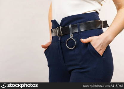 Business woman wearing suit, blue high waist pants with black leather trouser belt. Clothing detail.. Woman wearing high waist trouser with belt