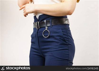 Business woman wearing suit, blue high waist pants with black leather trouser belt. Clothing detail.. Woman wearing high waist trouser with belt