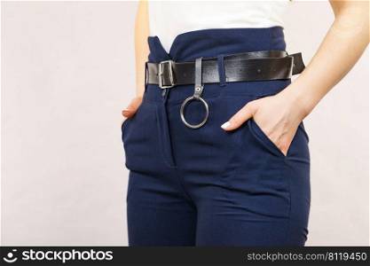 Business woman wearing suit, blue high waist pants with black leather trouser belt. Clothing detail.. Woman wearing high waist trouser with belt