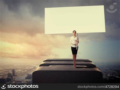 Business woman with banner. Image of business woman standing atop of building holding blank banner