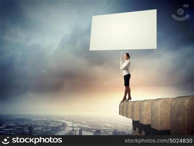 Business woman with banner. Image of business woman standing atop of building holding blank banner