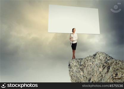 Business woman with banner. Image of business woman standing atop of hill holding blank banner