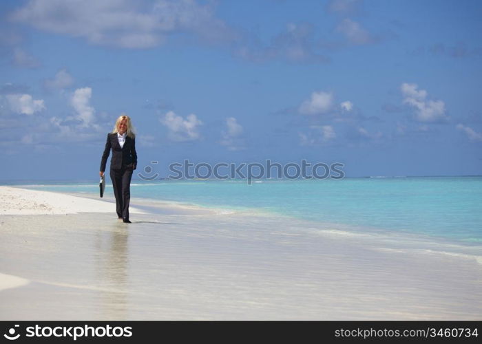 business woman with briefcase walking on the desolate ocean coast