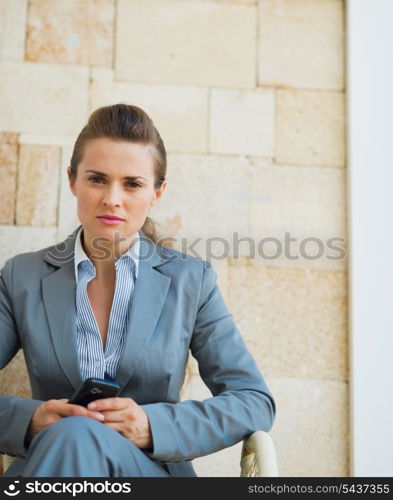 Business woman with cell phone sitting on terrace