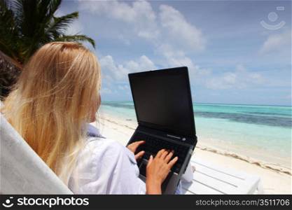 business woman with laptop lying on a chaise lounge in the tropical ocean coast