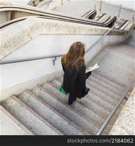 business woman with newspaper walking down stairs