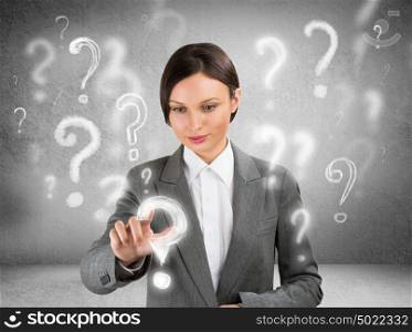 Business woman with question symbols around her. Choosing one and pressing on it