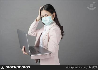 business woman with surgical mask is holding laptop computer