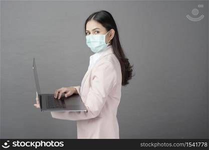 business woman with surgical mask is holding laptop computer