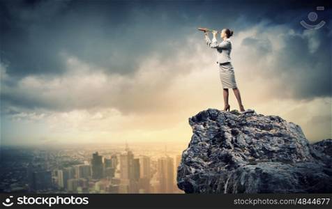 Business woman with telescope. Image of businesswoman looking in telescope standing a top of rock