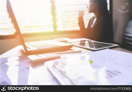 Business woman working in office and holding coffee cup by the window / Asian woman drinking coffee sitting at her working place , Nice coffee time