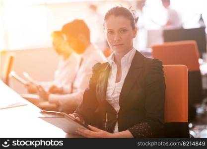 business woman working on desktop computer at modern startup office, people group in background with sunrise or sunset and sun flare in background