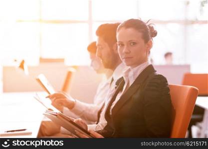 business woman working on desktop computer at modern startup office, people group in background with sunrise or sunset and sun flare in background