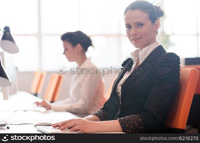 business woman working on desktop computer at modern startup office, people group in background