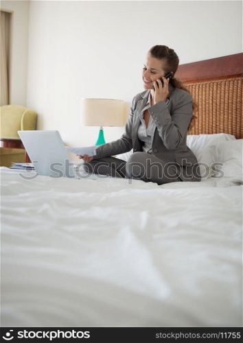 Business woman working with documents on bed in hotel room