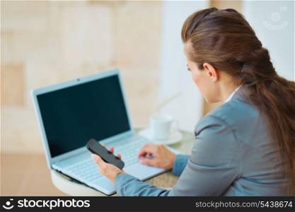 Business woman working with laptop on terrace. rear view