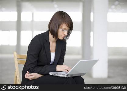 Business woman works on laptop in empty warehouse