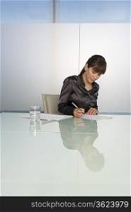 Business woman writing at table in conference room