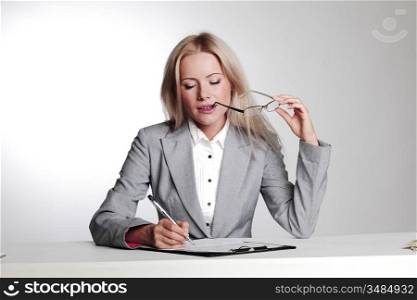 business woman writing in notebook on a gray background