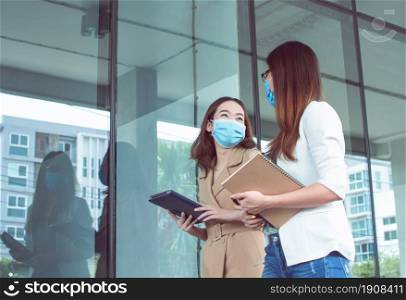 Business women are walking outside and talking together while wearing masks to protect virus. New Normal and Working concept.