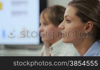 Business women talking during corporate presentation in meeting room, with charts and analitycs in background