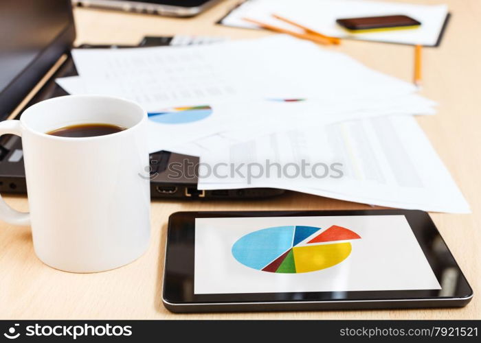 business workflow - mug of coffee and tablet pc with chart on office table